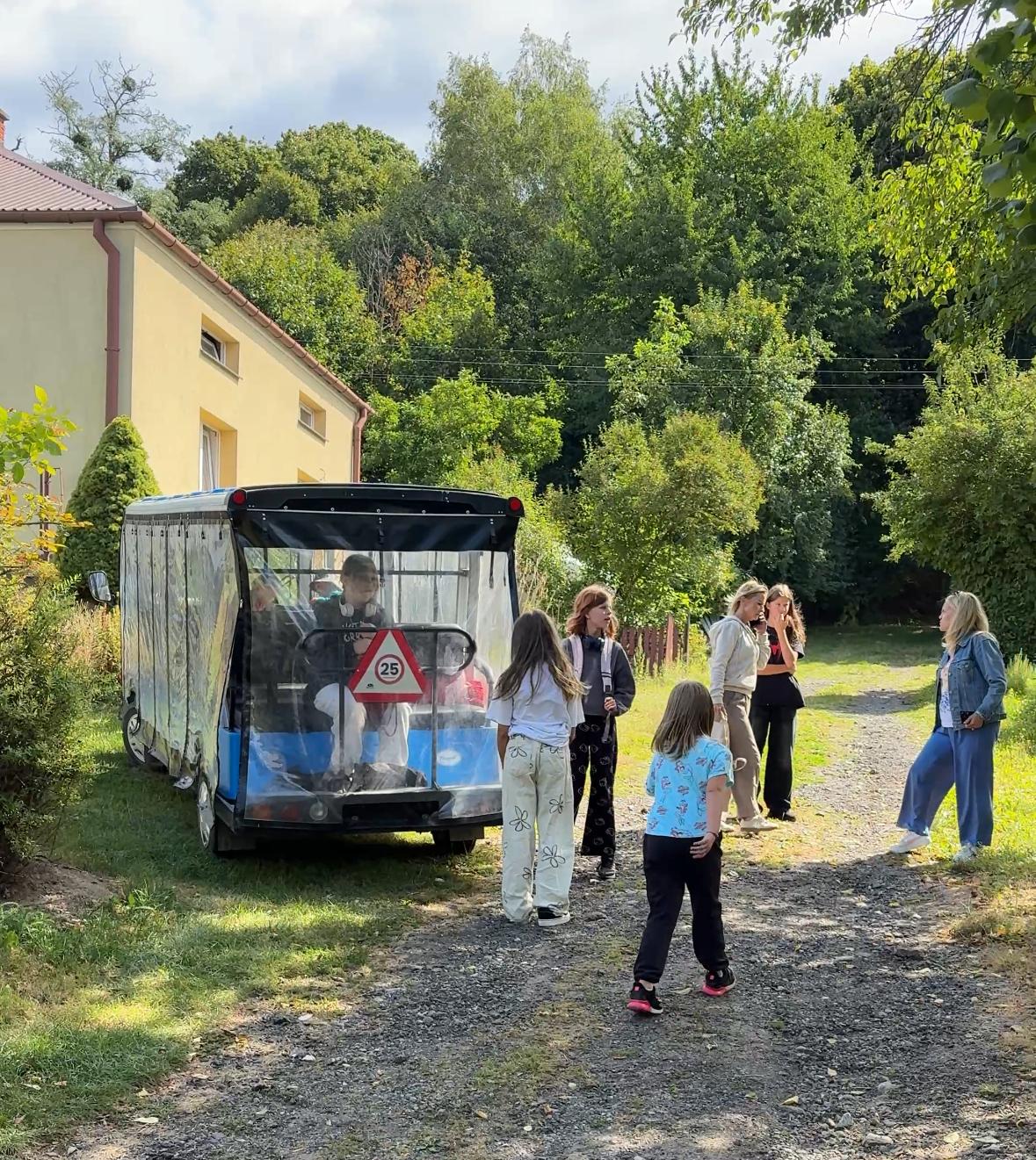Niebieski Ekobusik i biegające dzieci podczas postoju na wycieczce grupowej w okolicach Kazimierza Dolnego